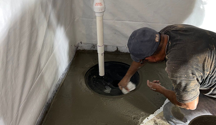 Professional worker installing sump pump in the basement Professional worker installing sump pump in the basement